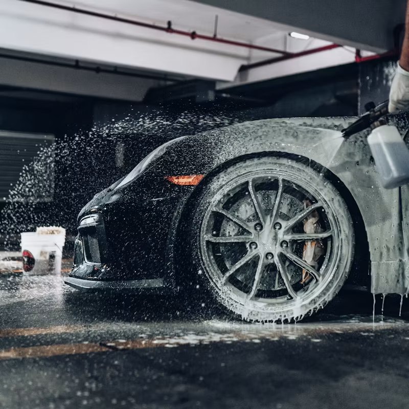 Black luxury vehicle covered in foam during a premium mobile detailing wash